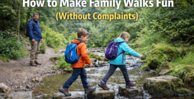 Two children walking left to right across stepping stones in a shallow woodland stream on a UK family walk while a parent watches nearby