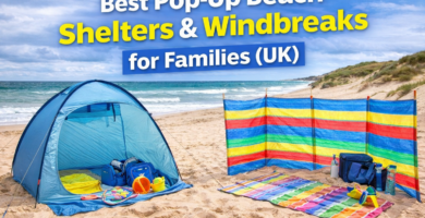 Pop-up beach shelter and colourful windbreak set up on a UK beach with towels and bags for a family beach day guide