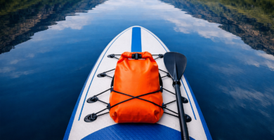dry-bag-paddle-board-scottish-loch.jpg Alt text: Orange dry bag clipped to an inflatable paddle board on a Scottish loch